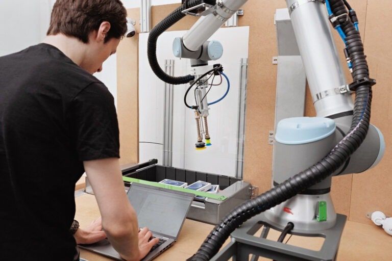 A Nomagic engineer on their laptop next to a Nomagic robot