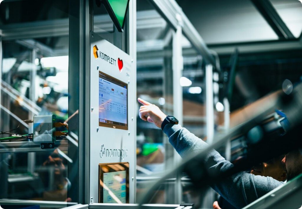 A hand pointing at a Nomagic control screen