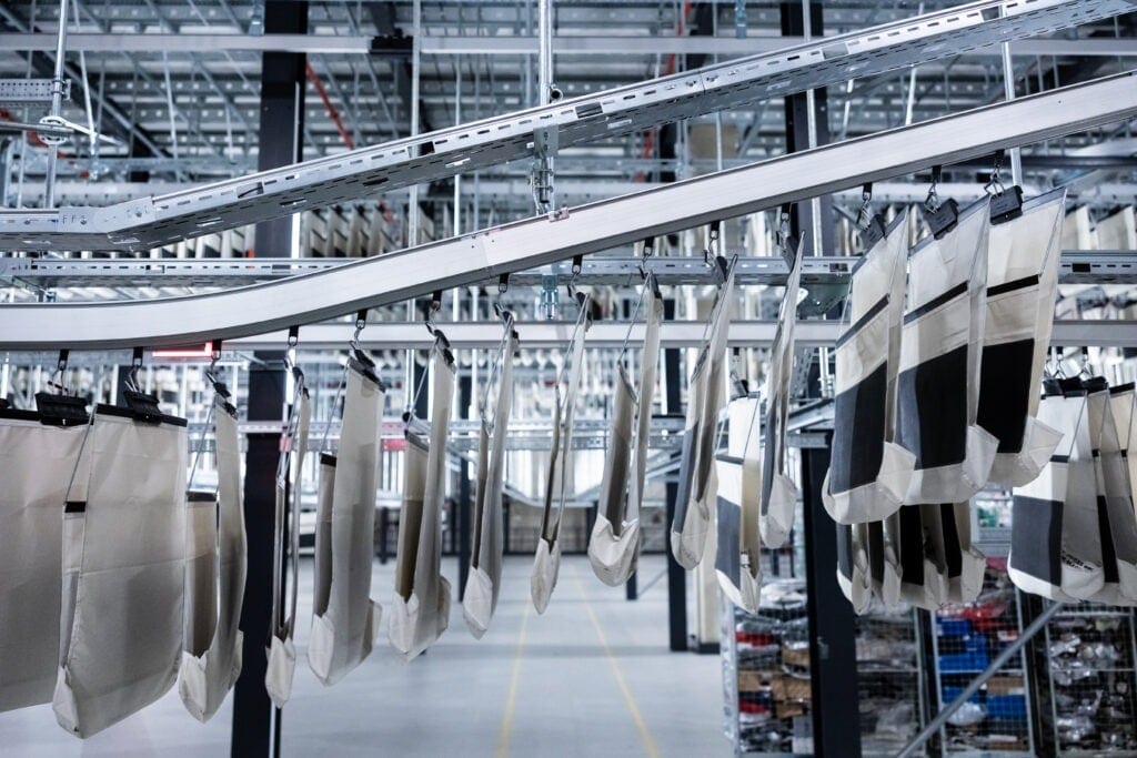 Des sacs de collecte sont suspendus à un convoyeur dans un entrepôt ASOS.