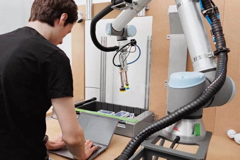 A Nomagic engineer on their laptop next to a Nomagic robot