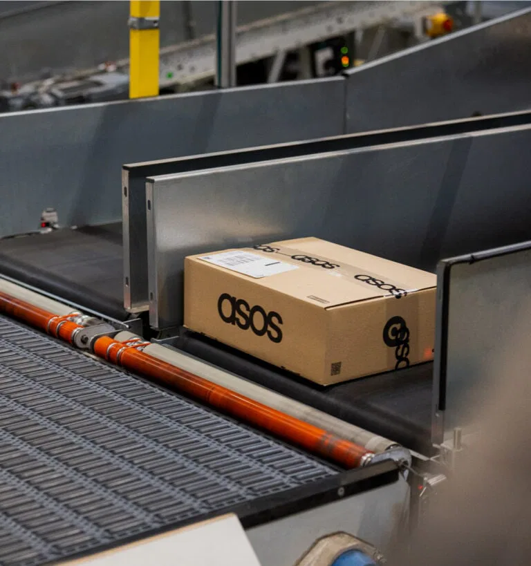 Un colis ASOS sur un tapis roulant dans un entrepôt, représentant la solution Nomagic Spot