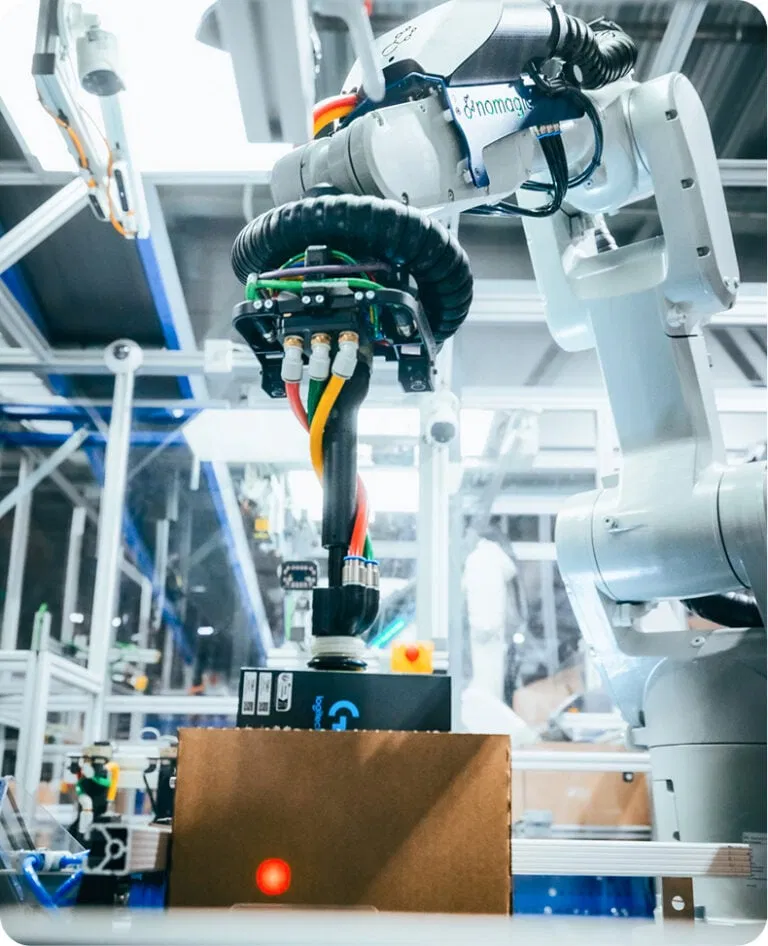 Un robot Nomagic emballe un carton prêt à être expédié.