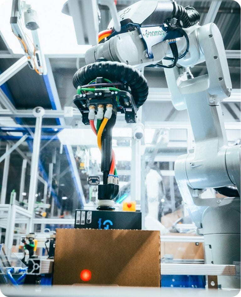 Un robot Nomagic emballe un carton prêt à être expédié.
